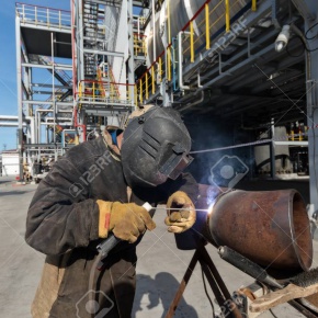 Welding works at installation of the new pipeline on oil refining installation with use of manual arc welding. Fisheye view